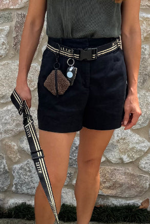 Person wearing black shorts with a hands free dog walking belt , dog lead in black and white standing against a stone wall
