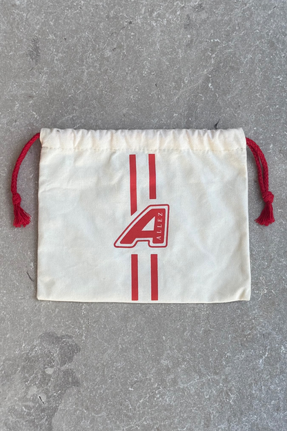 Allez White drawstring carry pouch with red logo  'A'  for Allez dogs on a grey surface. This pouch comes frre with every dog lead , hands free set or collar from Allez.